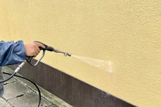 高圧洗浄機で外壁の汚れを洗い流すようす