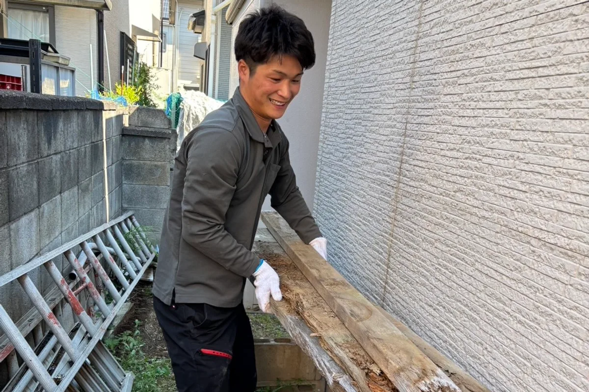 家のまわりに置かれた古い木材を運び出すスタッフ