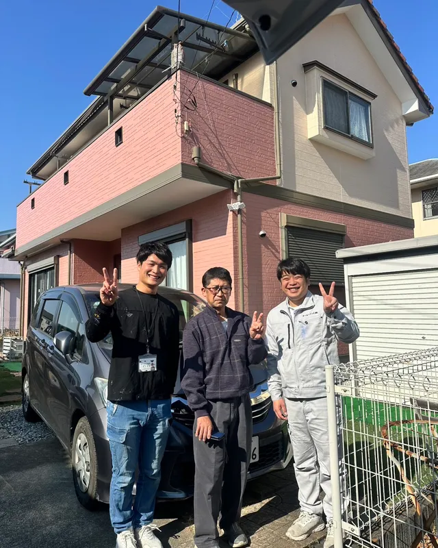 塗り替えたお住まいの前で、お客様とスタッフ3人でピースサイン