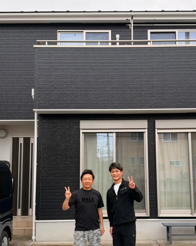黒い外壁に塗り替えたお住まいの前で、お客様とスタッフ
